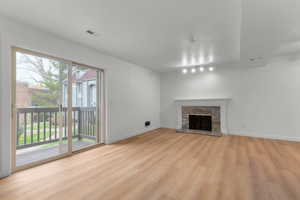 Unfurnished living room featuring light wood-style flooring and a stone fireplace
