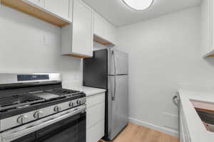 Kitchen with appliances with stainless steel finishes, light wood finished floors, and white cabinets