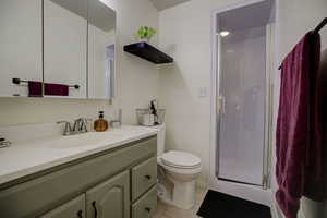 Ensuite 3/4 bathroom with light tile patterned flooring, a stall shower, and vanity