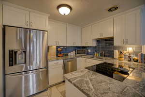 Updated kitchen featuring stainless steel appliances, white cabinets, flat top stove