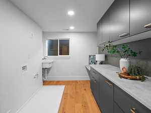 Laundry room with light wood finished floors and recessed lighting
