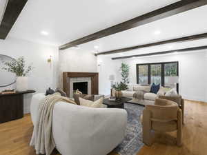 Living area featuring light wood-style floors, a premium fireplace, beam ceiling, and recessed lighting