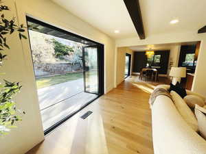 Living area featuring light wood-type flooring, beamed ceiling, recessed lighting, and a chandelier