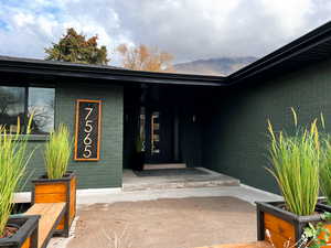 Entrance to property with brick siding, covered porch, and a mountain view