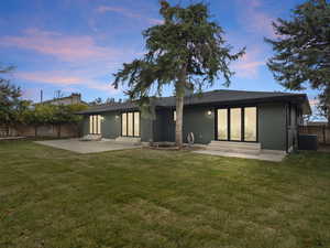 Back of house at dusk featuring a fenced backyard, entry steps, brick siding, and a patio