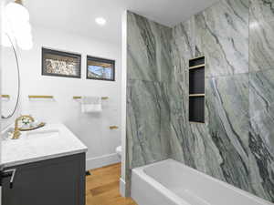 Bathroom featuring vanity, light wood-style floors, recessed lighting, and a combined bath / shower with marble appearance