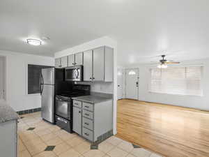 Kitchen featuring appliances with stainless steel finishes, gray cabinetry, light tile patterned floors, and a ceiling fan
