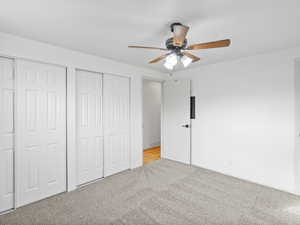 Upstairs bedroom featuring multiple closets, carpet floors, and ceiling fan