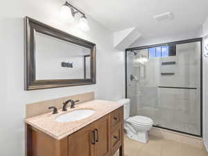 Bathroom with vanity, light tile patterned flooring, and a shower