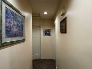 Corridor featuring dark carpet and baseboards