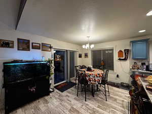 Dining space with light wood finished floors, a chandelier, and a textured ceiling