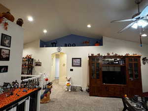Living area with arched walkways, lofted ceiling, carpet, recessed lighting, and a ceiling fan