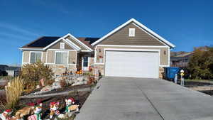Craftsman house featuring concrete driveway, a garage, roof mounted solar panels, and stone siding