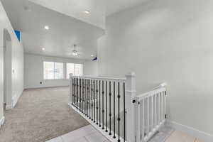 Corridor with vaulted ceiling, an upstairs landing, light colored carpet, arched walkways, and recessed lighting
