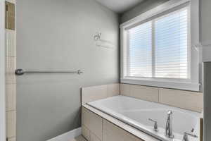 Full bath with a bath and baseboards