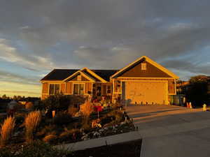 View of front of house featuring concrete driveway, roof mounted solar panels, and a garage