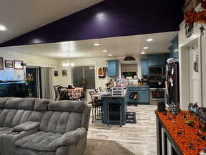 Living area featuring recessed lighting, light wood-type flooring, a chandelier, and lofted ceiling
