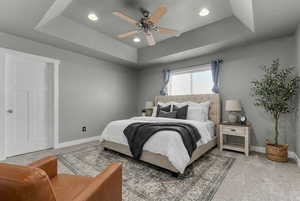 Carpeted bedroom with a raised ceiling, a ceiling fan, and recessed lighting