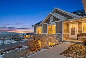 Snow covered property entrance with roof mounted solar panels and stone siding