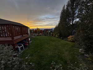 Yard at dusk featuring a yard and a deck