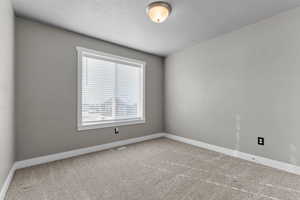 Carpeted empty room featuring baseboards and a textured ceiling