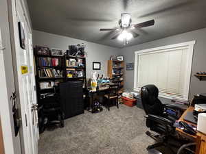Carpeted office space featuring a textured ceiling and a ceiling fan