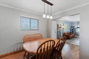 Dining room with wood finished floors and crown molding