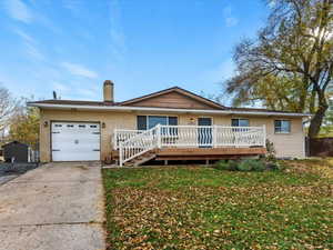 Ranch-style house featuring a deck, brick siding, concrete driveway, a chimney, and a garage