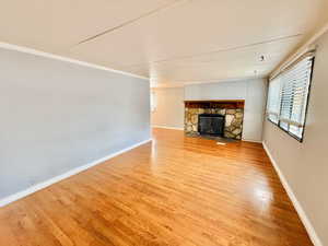 Unfurnished living room with light wood-style flooring and a stone fireplace