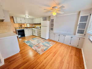 Kitchen with light countertops, white appliances, light wood-style floors, and ceiling fan