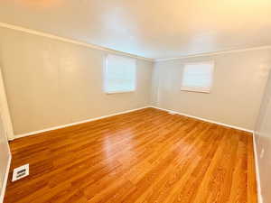 Empty room featuring light wood-type flooring and crown molding