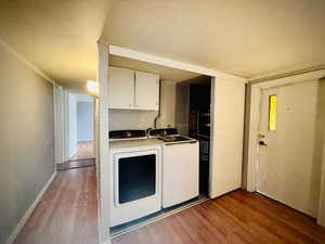 Laundry area with cabinet space, washing machine and clothes dryer, and light wood-type flooring