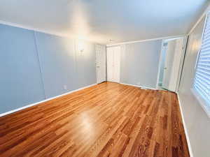 Spare room featuring wood finished floors, crown molding, and a textured ceiling