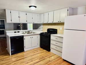 Kitchen featuring black appliances, light countertops, light wood finished floors, white cabinets, and a textured ceiling
