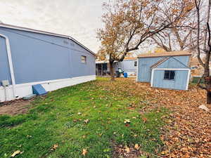 View of grassy yard with a storage unit