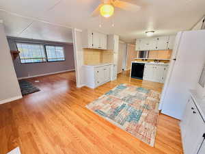 Kitchen featuring freestanding refrigerator, light wood-style floors, white cabinets, and light countertops