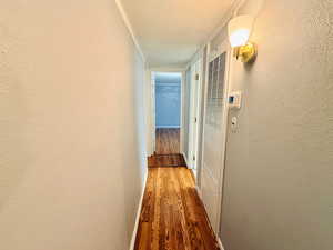 Hallway with wood finished floors, a heating unit, and a textured wall
