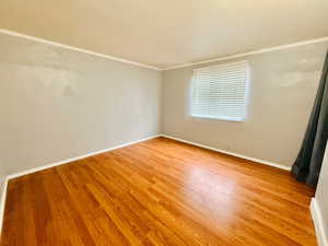 Spare room with light wood-type flooring and ornamental molding