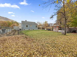 Rear view of house with a fenced backyard, a chimney, a mountain view, and an outbuilding