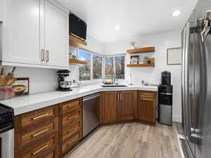 Kitchen featuring open shelves, appliances with stainless steel finishes, light wood-style flooring, recessed lighting, and brown cabinetry