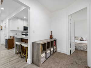Kitchen with white cabinetry, a kitchen breakfast bar, recessed lighting, appliances with stainless steel finishes, and light carpet