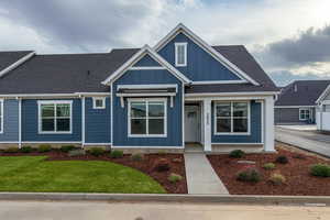 View of front of property with board and batten siding, a shingled roof, and a front lawn