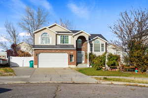 View of front of home featuring a gate, concrete driveway, brick siding, and a garage
