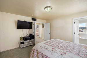 Carpeted bedroom featuring a textured ceiling and baseboards