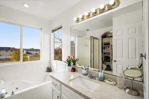 Full bathroom featuring a shower stall, vanity, a jetted tub, and a spacious closet