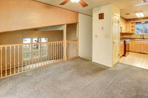Unfurnished living room featuring light carpet and a ceiling fan