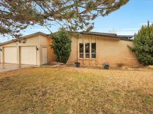 View of front of house with a front lawn, concrete driveway, and brick siding