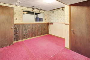 Spare room with wallpapered walls, a wainscoted wall, wood walls, and carpet