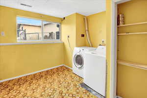 Washroom featuring light floors and washer and dryer