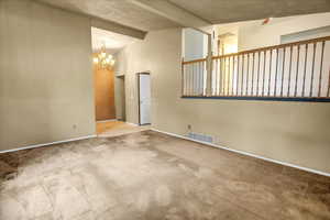 Carpeted spare room with a chandelier, beamed ceiling, a textured ceiling, and high vaulted ceiling